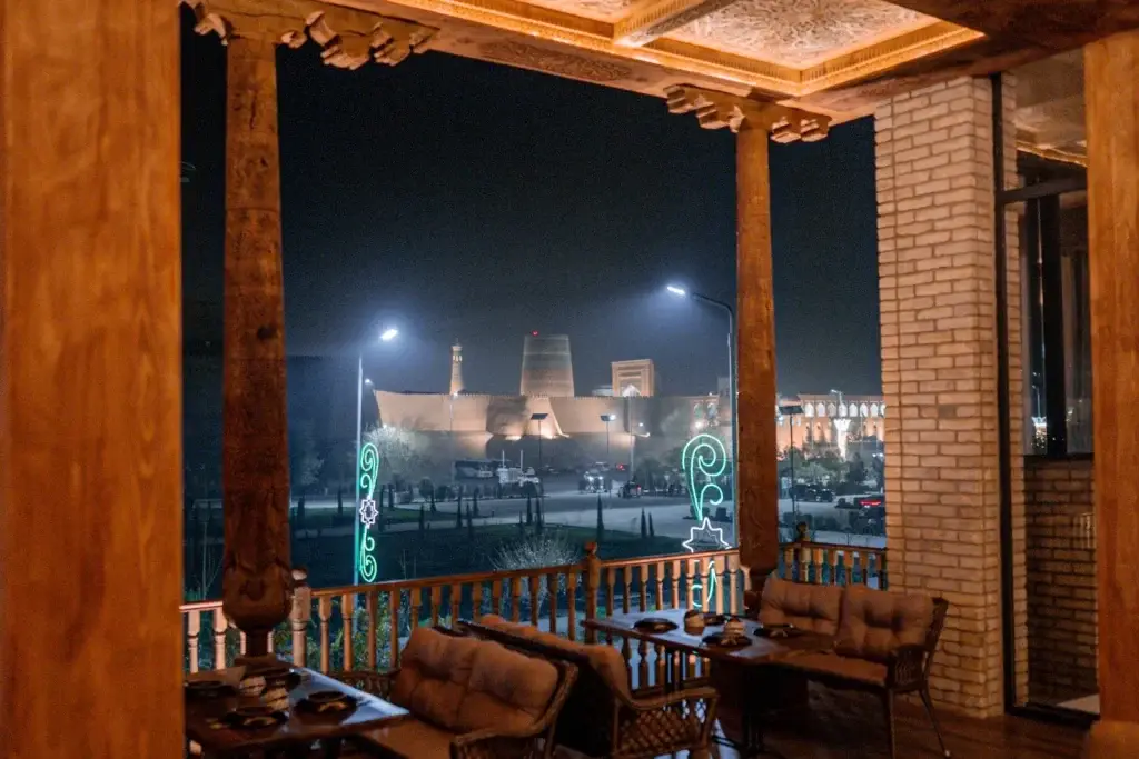 Xiva minaretlariga ko’ra keladigan kechki ko’rinishli restoran terasasi