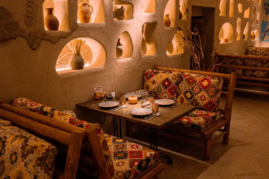 Sharqiy choyxona ichki dizayni, yumush sofalar va cho’ntak rangli o’yinlar bilan bezatilgan