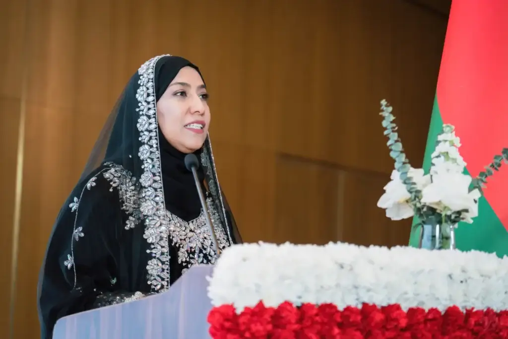 Женщина в традиционном оманском наряде выступает за трибуной во время официального мероприятия