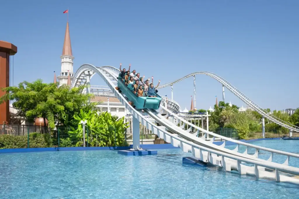 People riding a water roller coaster at a theme park on a sunny day