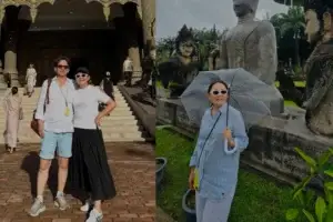 Люди позируют у входа в украшенный традиционной резьбой лаосский храм и женщина с прозрачным зонтом возле статуй Будды в парке среди зелени