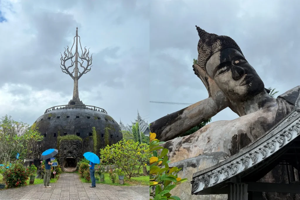 Entrance to the dome-shaped sculpture with a tree-like spire and tourists holding blue umbrellas, next to a large reclining Buddha statue in a garden setting under cloudy sky