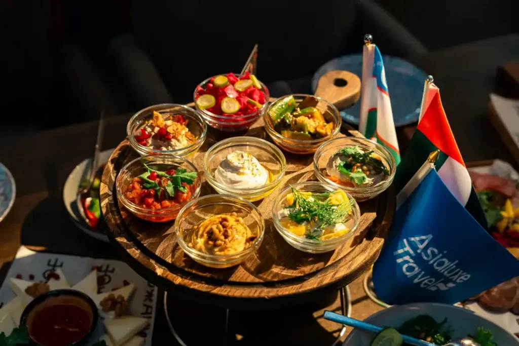 Деревянная подставка с ассорти восточных закусок в стеклянных пиалах, украшенная миниатюрными флагами, включая флаг с логотипом Asialuxe Travel