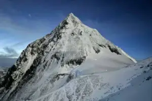 A snow-covered mountain peak against a clear blue sky, showcasing the power and beauty of nature