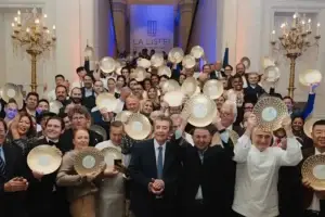 LA LISTE 2025 Award ceremony: a group of people with golden award plates in a luxurious hall with chandeliers.