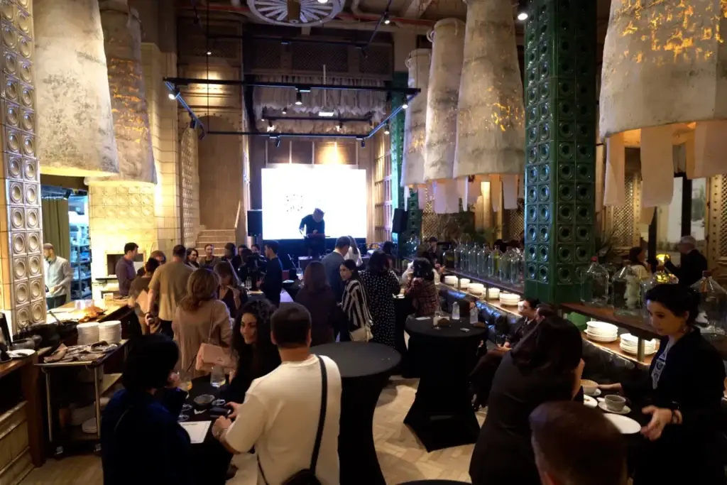 Гости общаются в ресторане в стиле лофт, на заднем плане — сцена с экраном