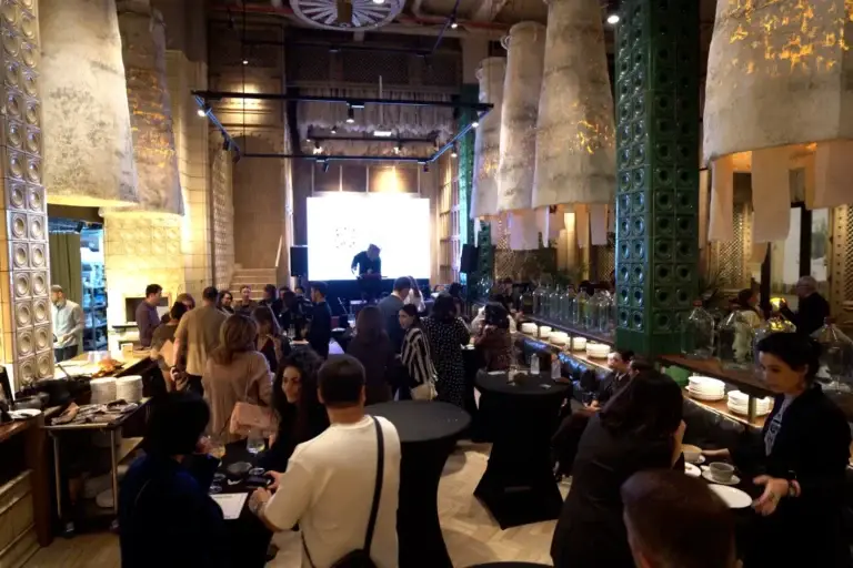 Гости общаются в ресторане в стиле лофт, на заднем плане — сцена с экраном