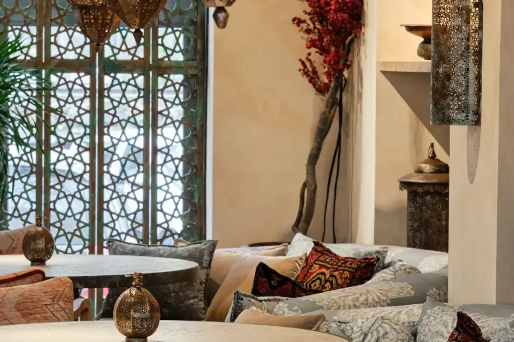 Интерьер в восточном стиле: диваны с подушками, низкие столы, ажурные светильники, резная перегородка, декоративная ветка с красными ягодами