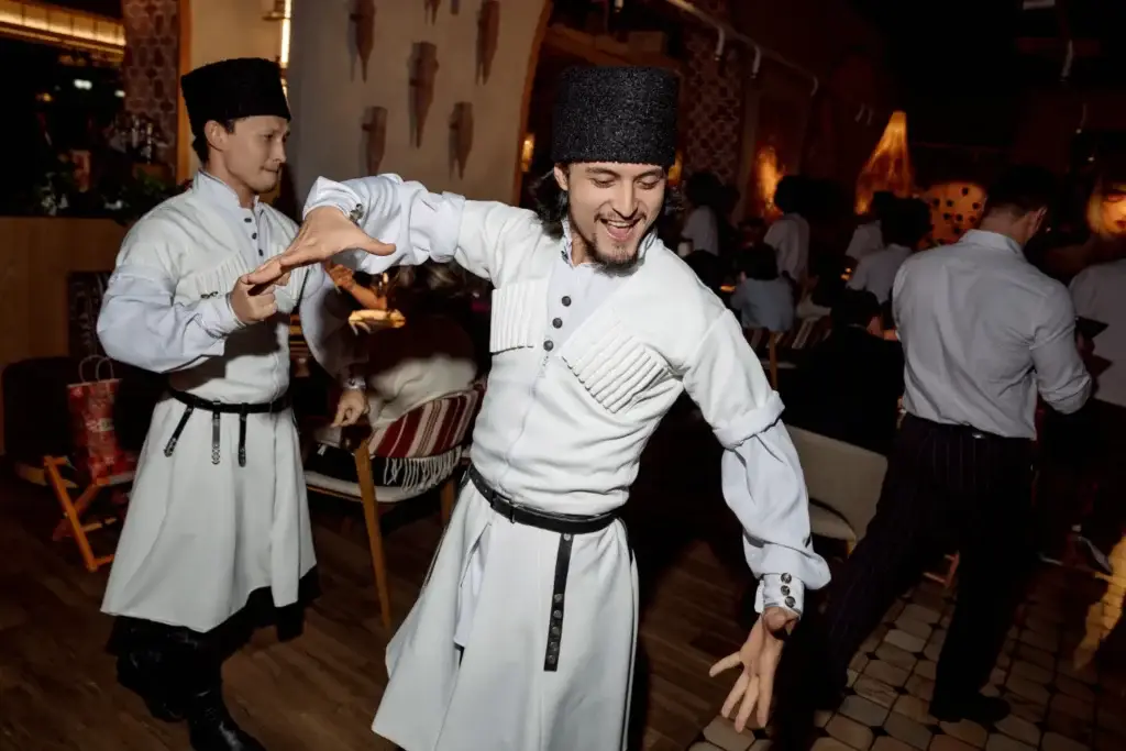 Two dancers in Caucasian traditional attire performing a traditional dance