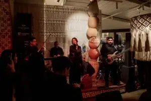 Группа музыкантов выступает на сцене, вокалистка поёт в микрофон