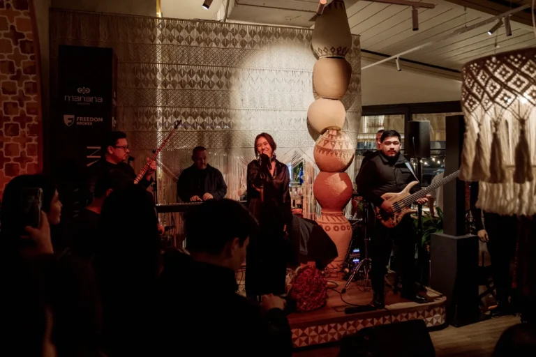 Группа музыкантов выступает на сцене, вокалистка поёт в микрофон