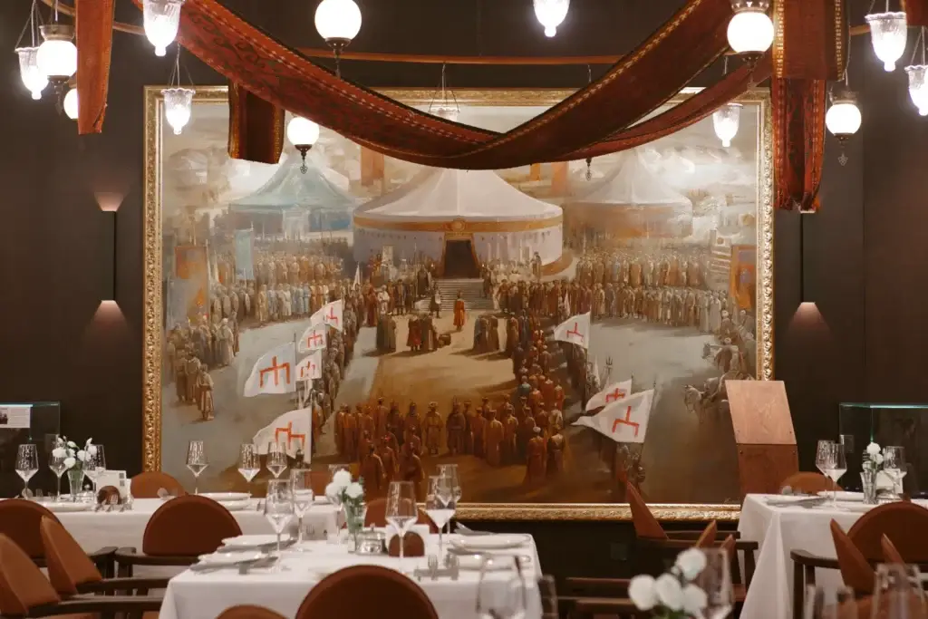 Ресторанный зал с картиной «Пленение Шамиля» Теодора Горшельта на стене. Сервированные столы, текстильные драпировки, подвесные светильники
