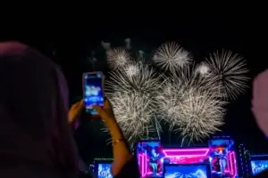 A girl, with her back to the camera, shoots colorful fireworks at a festival in Dubai