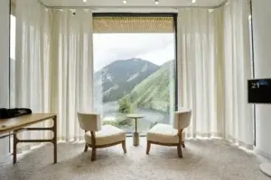 Interior of a guest room with a panoramic window overlooking mountains and a lake in a nature-based hotel in Kazakhstan