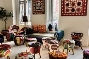 Living room featuring Suzani furniture: poufs, armchairs, sofa with ethnic patterns, decorative wall panels