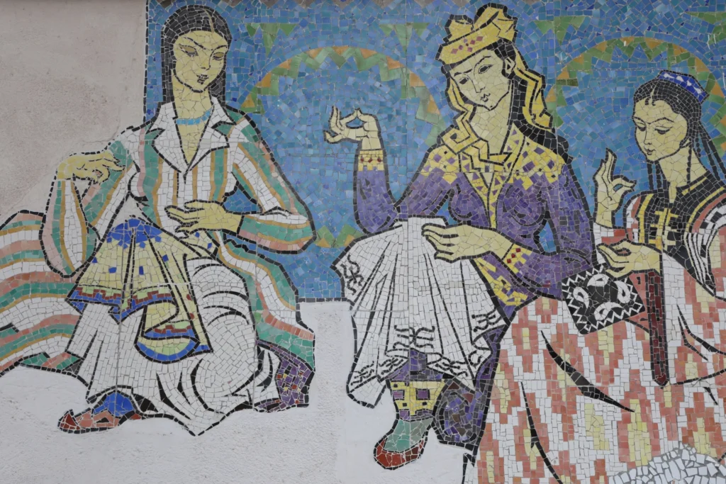 Colorful mosaic wall panel depicting three women in traditional Uzbek dress performing a folk dance against a blue patterned background