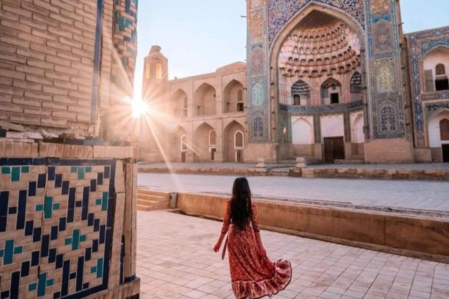 Девушка на фоне медресе под лучами восходящего солнца