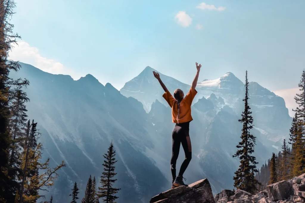 The girl throws up her arms against the background of the mountains