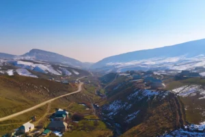 Mountainous terrain viewed from above, with houses and snow-covered peaks