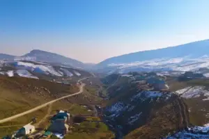 Горная местность с высоты с домами и снегом на вершине