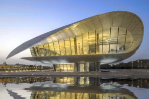 Современное изогнутое здание Музея Этихад с отражением в воде на закате дня