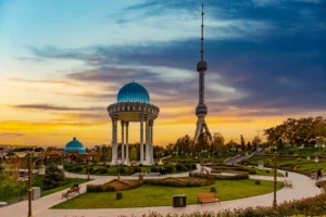 View of the Tashkent TV Tower and the memorial complex commemorating victims of repression with a blue rotunda at sunset in Tashkent, Uzbekistan